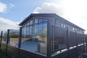 a large house with a large deck with glass at Padstow Lodge - Padstow Holiday Village in Padstow