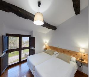 a bedroom with a large white bed and a window at Casa de Aldea Casina del Naranjo in Linares