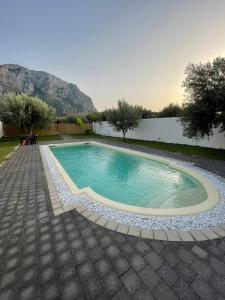 una piscina in un cortile con montagne sullo sfondo di B&B Santorini a Cinisi