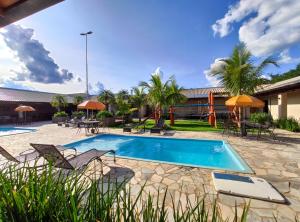 a resort pool with chairs and tables and a playground at Hotel Pousada Parque das Águas in Olímpia