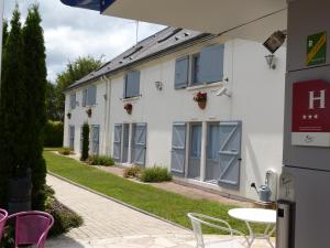 a building with grey windows and a table and chairs at Logis Hôtel Alizéa Le Mans Nord in Saint-Saturnin