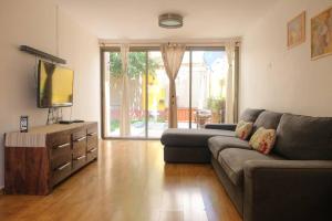 uma sala de estar com um sofá e uma televisão em Cosy Family Home & Garden in Eilat em Eilat