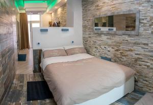 een bed in een kamer met een bakstenen muur bij Catalani Charme Apartament in Cagliari