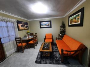 Una sala de estar con un sofá naranja y una mesa. en Departamento INCA PALACE EXPERIENCE, en Puno