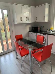 a kitchen with a glass table and red chairs at Nairoo in Balloch