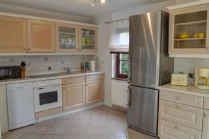 a kitchen with wooden cabinets and a stainless steel refrigerator at Haus Sonnenschein in Zingst