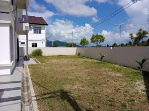 a backyard of a white house with a fence at D'Corner Homestay Kluang Perdana in Kluang