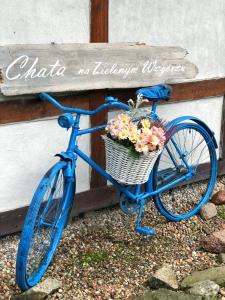 Una bicicleta azul con una cesta llena de flores en Chata na Zielonym Wzgórzu en Garcz