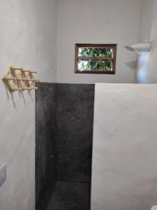 a bathroom with a window and a black and white wall at Recanto da Alice in Trancoso