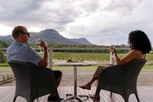 Un uomo e una donna seduti a un tavolo a bere vino di Leogate Estate Villas a Pokolbin