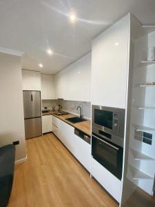 a kitchen with white cabinets and a stainless steel appliance at Rooftop Sunset View Apartment in Tirana