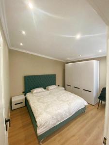 sypialnia z dużym łóżkiem z zielonym zagłówkiem w obiekcie Rooftop Sunset View Apartment w Tiranie