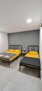 怡保的住宿－Guesthouse @ Ipoh garden II，配有黄色床单的客房内的两张床