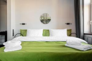 a green bed with white sheets and towels on it at Бутик-отель География in Irkutsk
