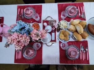a table with a table cloth with breakfast foods and flowers at Hostel Portal Das Fadas in Cavalcante