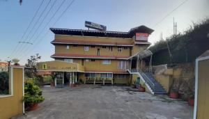 a large yellow building with stairs in front of it at HOTEL CAVERI COMFORT INN in Madikeri