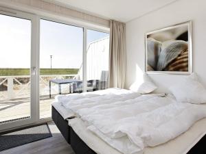 a white bedroom with a large bed and a balcony at 4 person holiday home in Wendtorf in Wendtorf