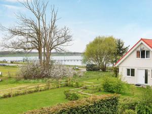 a white house with a fence next to a body of water at 8 person holiday home in Gelting in Gelting