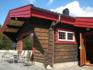 uma cabana de madeira com um telhado vermelho e um pátio em 9 person holiday home in H LLEVIKSSTRAND em Hälleviksstrand