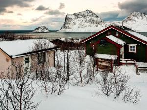 a house in the snow with mountains in the background at 5 person holiday home in LEKNES in Leknes