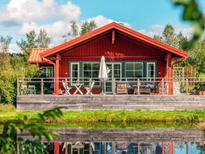 a red house with a deck and a umbrella at 6 person holiday home in BODAFORS in Västrahyn