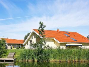 オッテルンドルフにある12 person holiday home in Otterndorfの水の隣のオレンジの屋根の家