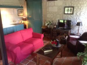 a living room with a red couch and a tv at Former customs house with large garden and private pool 4 km from Chinon in La Roche-Clermault