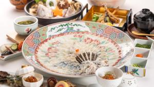 下関市にあるHotel Sumire ふぐ料理を愉しむ料理宿の他の料理と一緒にテーブルの上に置かれた大きな皿の食べ物