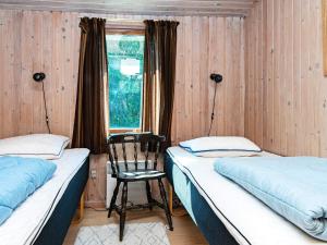 two beds in a room with a chair and a window at 6 person holiday home in Glesborg in Bønnerup