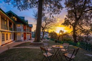 a table and chairs in a yard with a sunset at Nau Nabh Cottage by VEO - Part of StayVista in Shimla