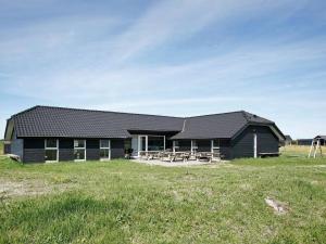 un edificio negro con un campo de césped delante de él en Ten-Bedroom Holiday home in Brovst, en Brovst