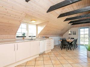 una cocina con armarios blancos y una mesa con sillas. en 8 person holiday home in Ringk bing, en Klegod