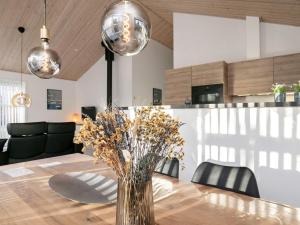 8 person holiday home in L s في Læsø: طاولة غرفة الطعام مع إناء من الزهور عليها