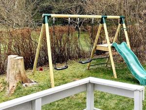 un parque infantil con un columpio en un patio en 10 person holiday home in F rvang, en Fårvang