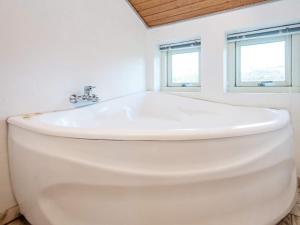 a white bath tub in a bathroom with two windows at 8 person holiday home in Juelsminde in Sønderby