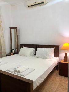 - une chambre avec un lit doté de draps blancs et d'une lampe dans l'établissement Blue Bird Apartment, à Negombo