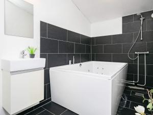 La salle de bains est pourvue d'une baignoire blanche et d'un lavabo. dans l'établissement 16 person holiday home in Brovst, à Brovst