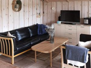 a living room with a black leather couch and a table at 5 person holiday home in R dby in Kramnitse