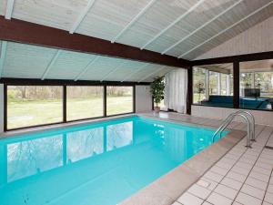 uma grande piscina com água azul e janelas em Three-Bedroom Holiday home in Bindslev 3 em Bindslev