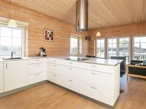 a kitchen with white cabinets and wooden walls at 10 person holiday home in Bagenkop in Bagenkop
