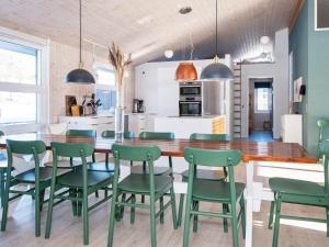 a kitchen and dining room with a wooden table and green chairs at Five-Bedroom Holiday home in Ebeltoft 3 in Ebeltoft