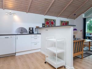 8 person holiday home in Haderslev في Kelstrup Strand: مطبخ مع دواليب بيضاء وطاولة في الغرفة