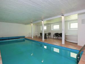 a large swimming pool with a table and chairs at Cozy Holiday Home in Thyholm with Swimming Pool in Thyholm