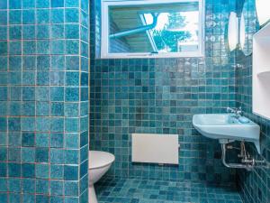 a blue tiled bathroom with a toilet and a sink at 6 person holiday home in N rre Nebel in Lønne Hede