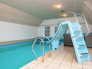 a swimming pool with a slide next to a swimming pool at 18 person holiday home in Ulfborg in Øby