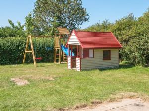 a playground with a house and a swing at 10 person holiday home in Juelsminde in Sønderby