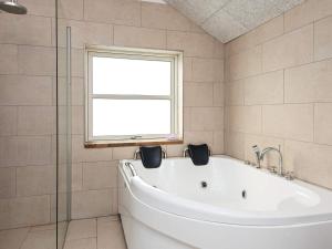 a white bath tub in a bathroom with a window at 8 person holiday home in Ulfborg in Fjand Gårde