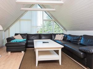 a living room with a black leather couch and a table at 8 person holiday home in Ulfborg in Fjand Gårde