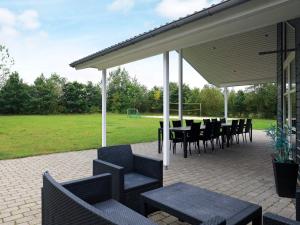 eine Terrasse mit einem Tisch, Stühlen und einem Fußballfeld in der Unterkunft 14 person holiday home in H jslev in Bøstrup