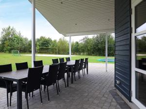 eine Terrasse mit einem Tisch, Stühlen und einem Fußballfeld in der Unterkunft 14 person holiday home in H jslev in Bøstrup
